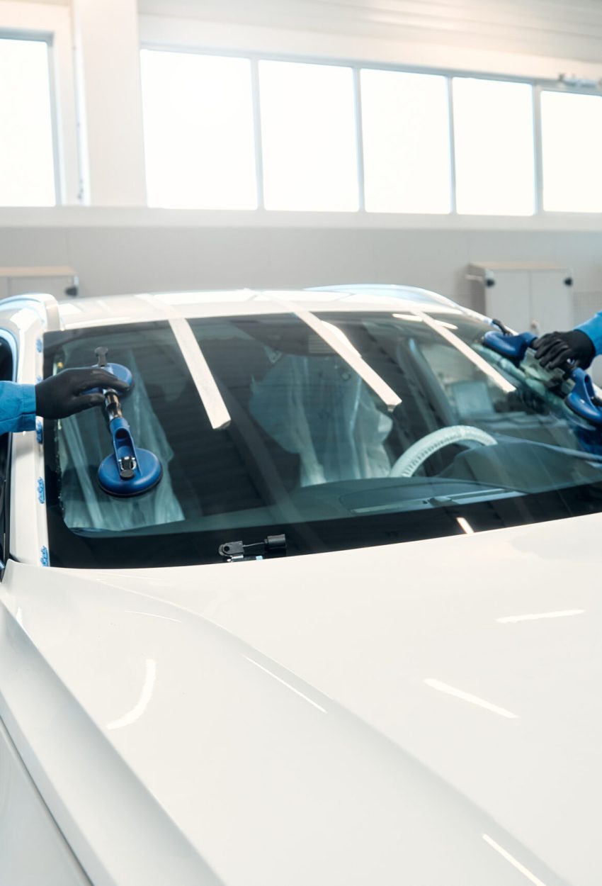 Auto repair and maintenance. A professional mechanic changes a windshield on a car in a car workshop. Hands mechanic holding a tool. Replacement of automobile glasses.